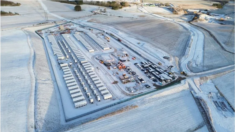 Aerial view of snowy industrial site with vehicles.