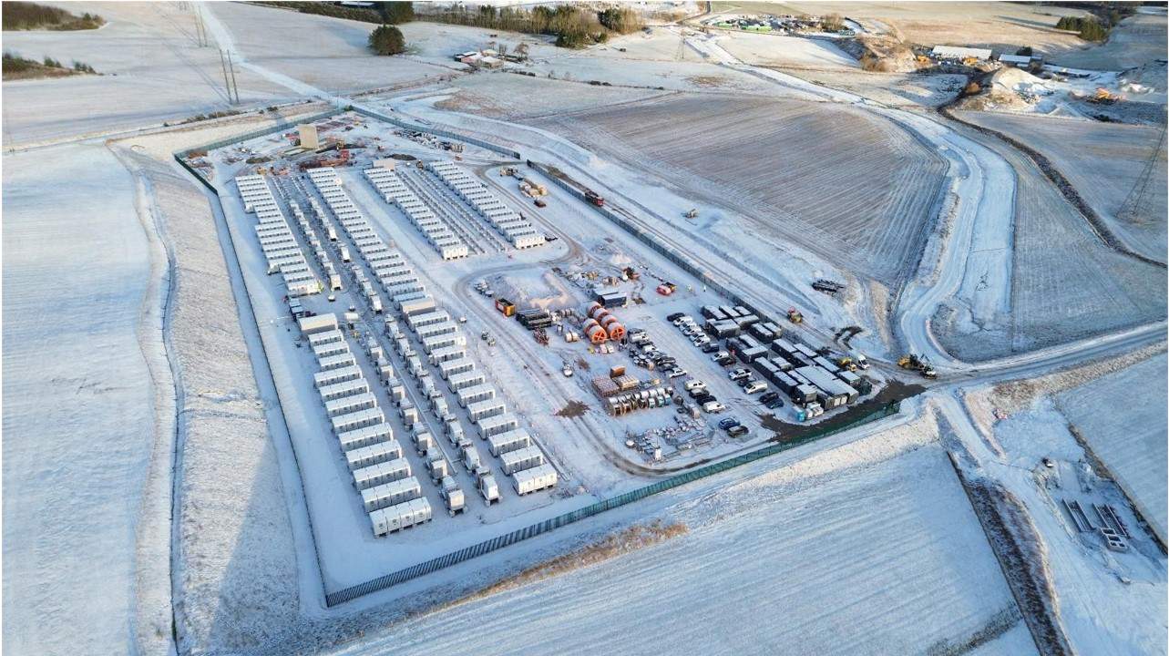 Flyfoto av et snødekt industriområde med kjøretøy.