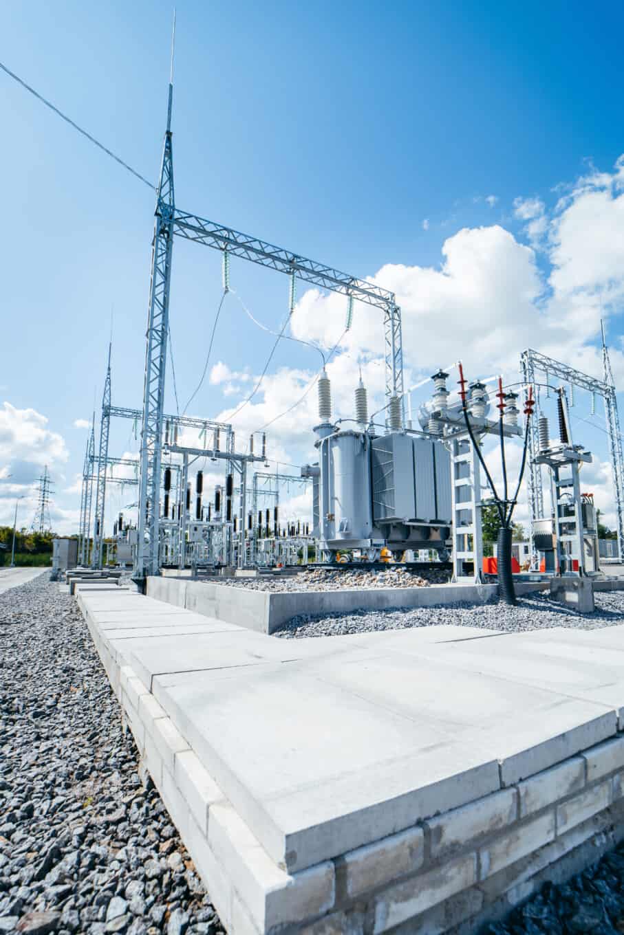 Electrical substation with transformer and power lines, sunny day.