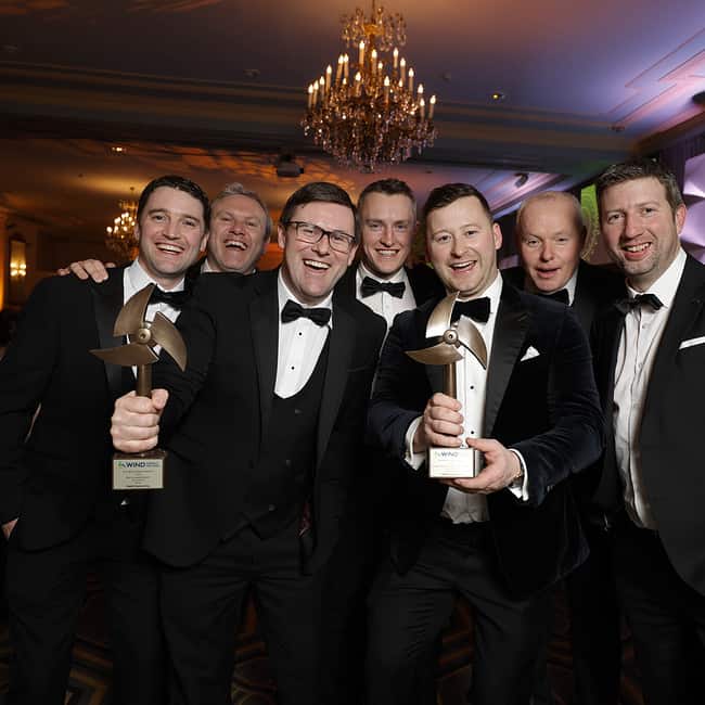 Grupo de hombres de esmoquin posando con premios.